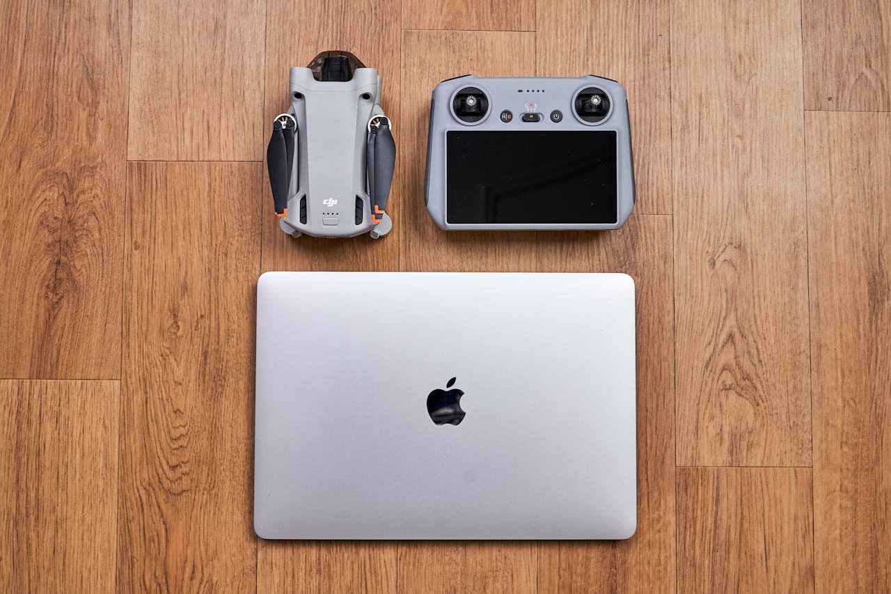 Overhead shot of a drone, controller, and laptop on a wooden floor